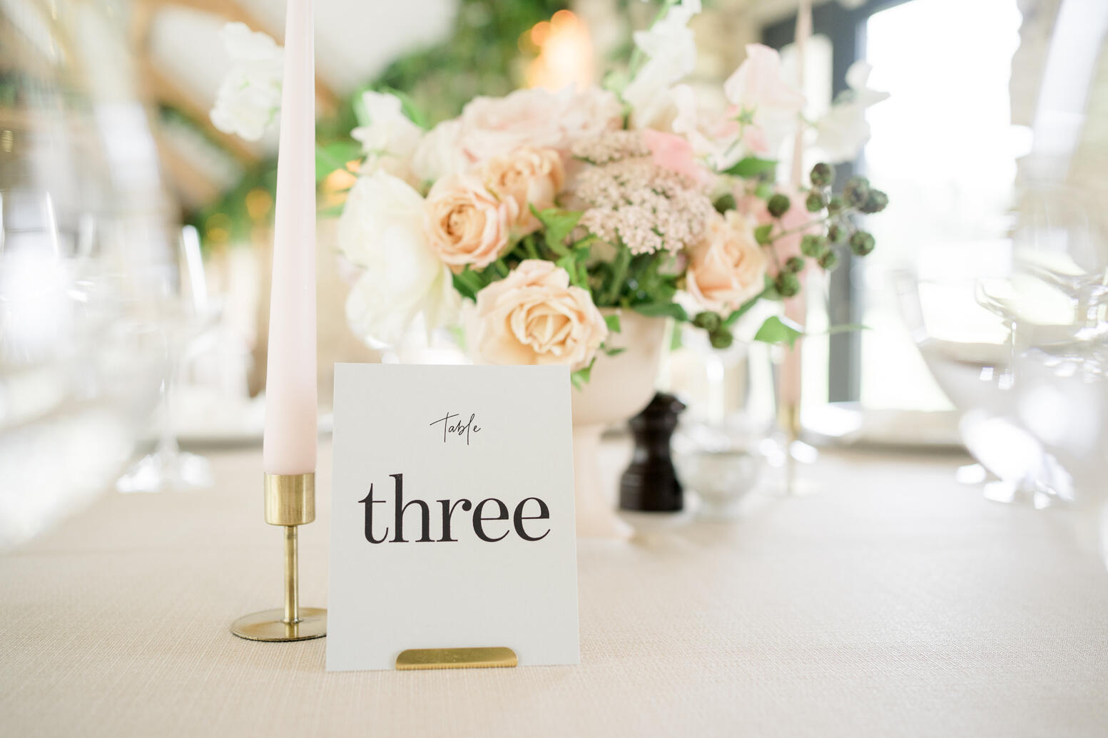 Table number and pink dinner candle in a brass holder