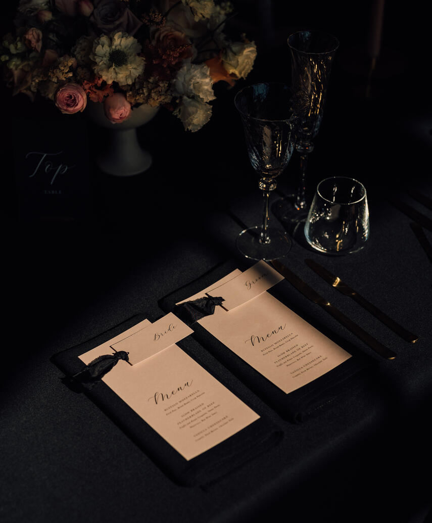 black table linen with a pink menu and place name on top